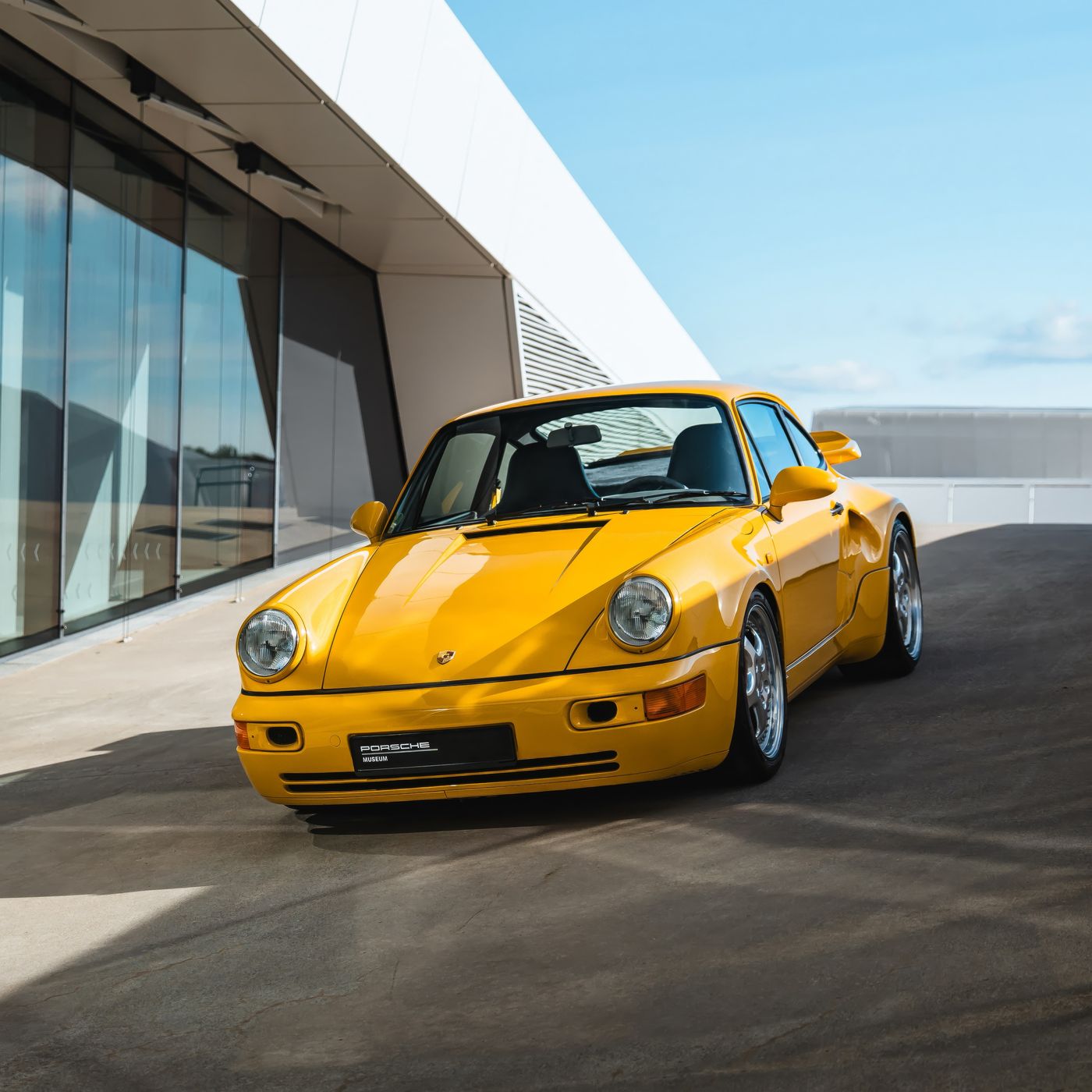 Yellow air-cooled 911 outside a modern museum, interlaced in 3D depth